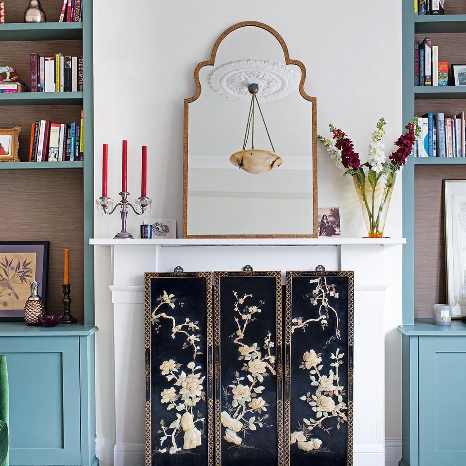 Living room with blue built in cupboards, fireplace and antique mirror.