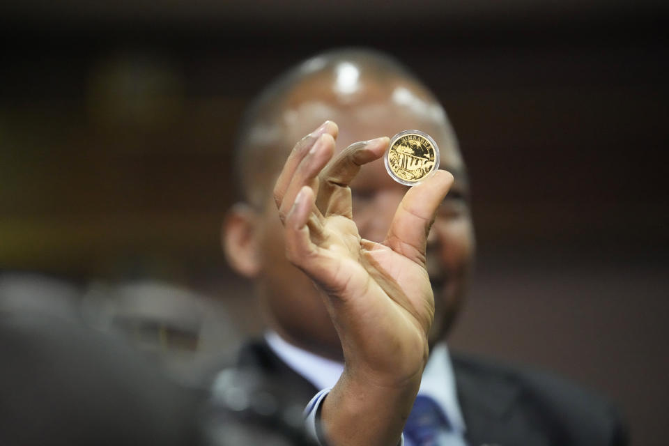 Reserve Bank of Zimbabwe Governor, John Mangudya holds a sample of a gold coin at the launch in Harare, Monday, July, 25, 2022. Zimbabwe has launched gold coins to be sold to the public in a bid to to tame runaway inflation that that has further eroded the country's unstable currency. (AP Photo/Tsvangirayi Mukwazhi)