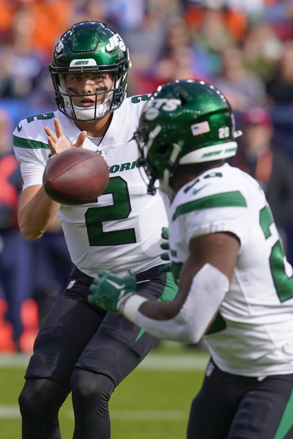 New York Jets quarterback Zach Wilson (2) tosses the ball to New York Jets running back Breece Hall (20) during the first half of an NFL football game between the Denver Broncos and the New York Jets, Sunday, Oct. 23, 2022, in Denver. (AP Photo/Matt York)