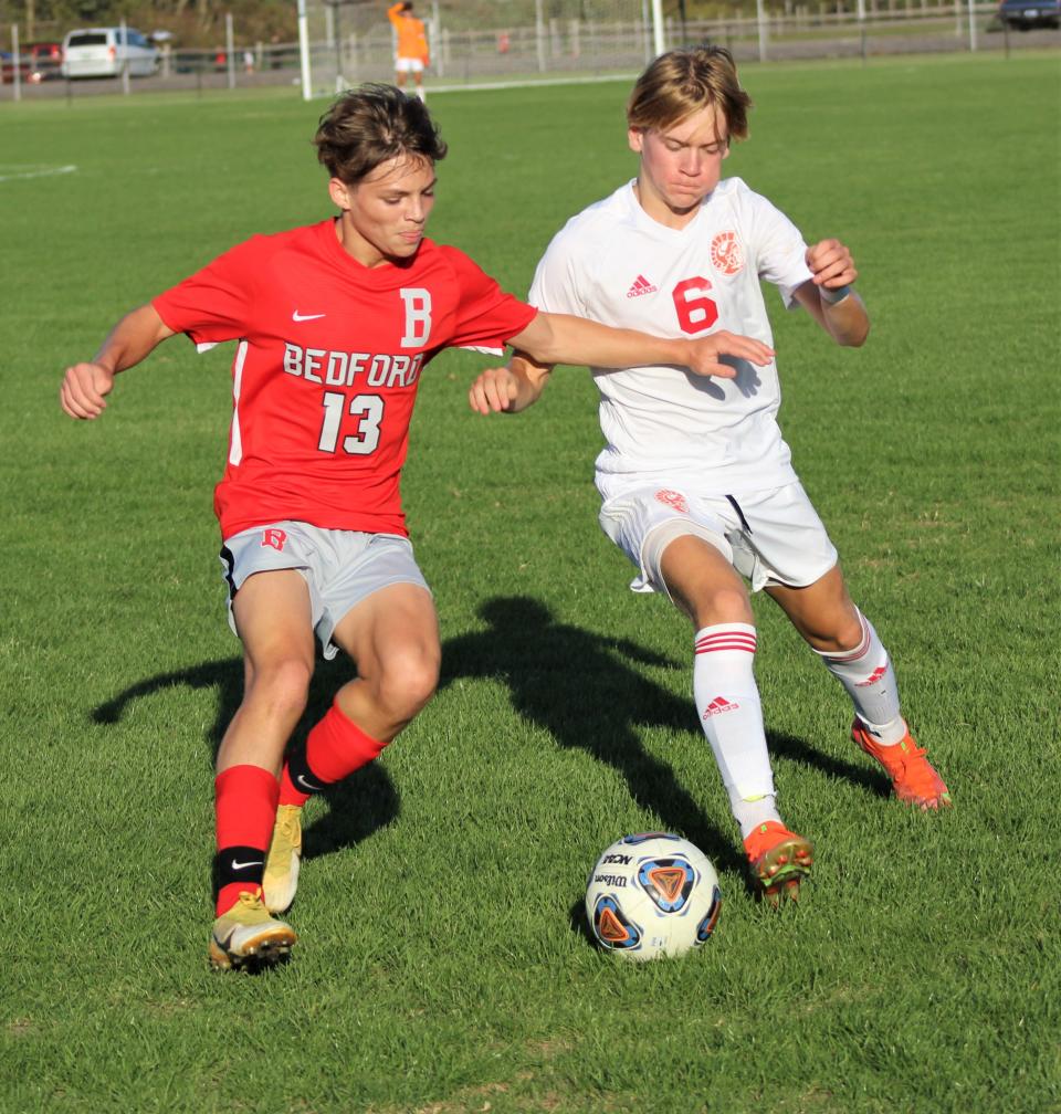 Bedford's Zach Janowicz (13) fights for a loose ball with Monroe's Talen Swinkey last season.