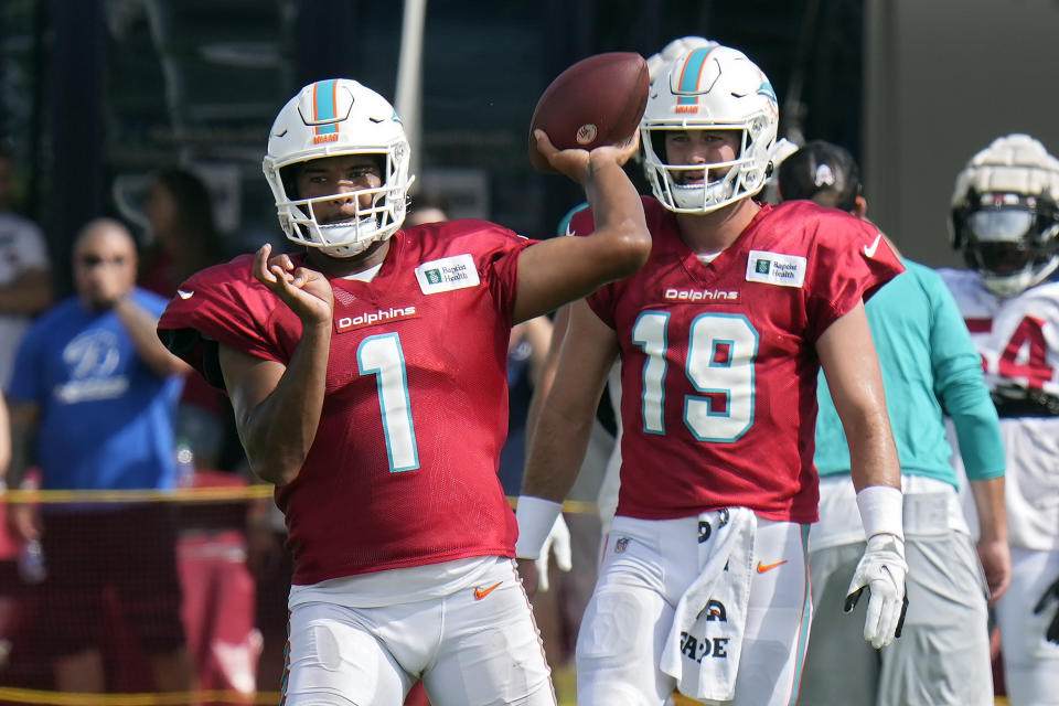 Miami Dolphins quarterback Tua Tagovailoa (1) throws a pass during an NFL football training camp practice with the Tampa Bay Buccaneers Wednesday, Aug. 10, 2022, in Tampa, Fla. Looking on is quarterback Skylar Thompson (19). (AP Photo/Chris O'Meara)