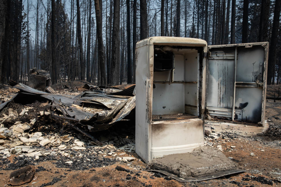 A burned and empty refrigerator sits amid fire-strewn rubble