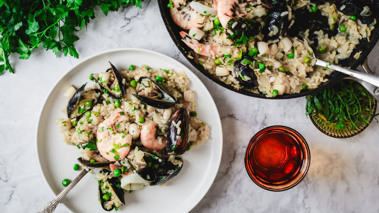 A plate and a pan of seafood risotto with wine and herbs