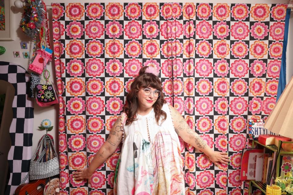 Sam Reece stands in front of a pink floral curtain in her crafting studio.