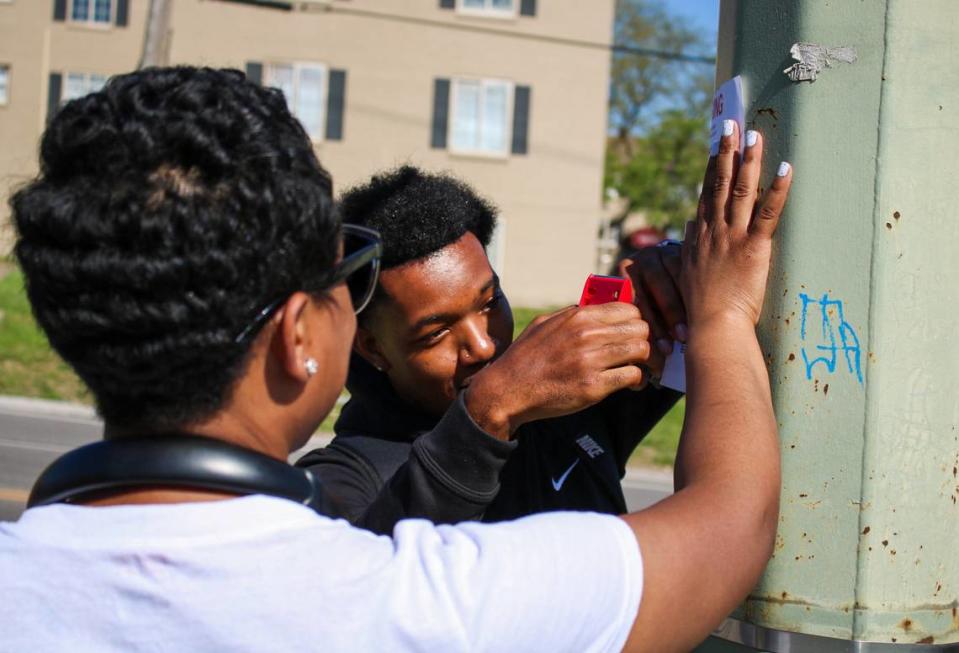 Steven Wright and Denisha Jones hang fliers along Troost Avenue with information about missing person T’Montez Hurt. He has been missing since Easter.