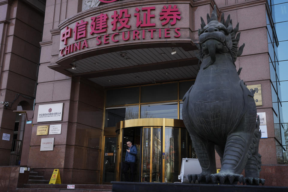 A man browses his smartphone as he walks out from a brokerage house in Beijing, Tuesday, Feb. 6, 2024. A Chinese state investment fund has promised to expand its purchases of stock index funds to help markets that have been sagging under heavy selling pressure from a property crisis and slowing economy. (AP Photo/Andy Wong)