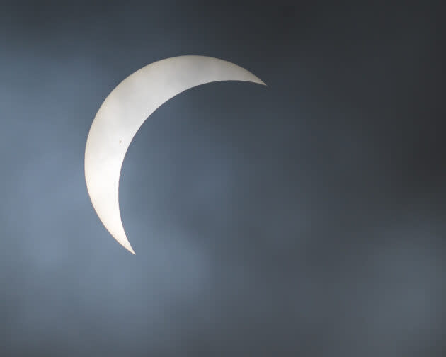 Clouds partially obscure the view of the solar eclipse’s partial phase, as seen from Arkansas. You can just make out a sunspot near the edge of the moon’s dark disk. (GeekWire Photo / Kevin Lisota)