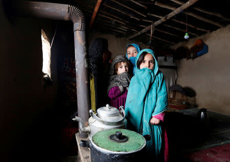 Internally displaced Afghan girls warm themselve inside their shelter during a snowfall in Kabul, Afghanistan February 5, 2017. REUTERS/Mohammad Ismail