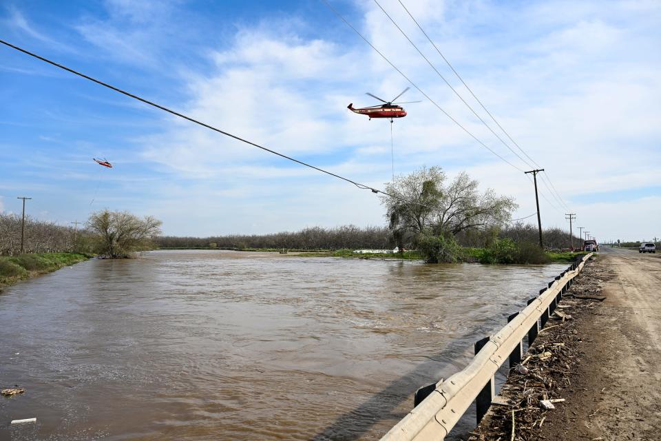 Helicopters from Siller work with crews below to shore up banks of the Tule River Friday, March 17, 2023 at Road 192 just north of Avenue 168 and east of Woodville. Road closures are common in south Tulare County. Flood warnings have been issued for many areas.