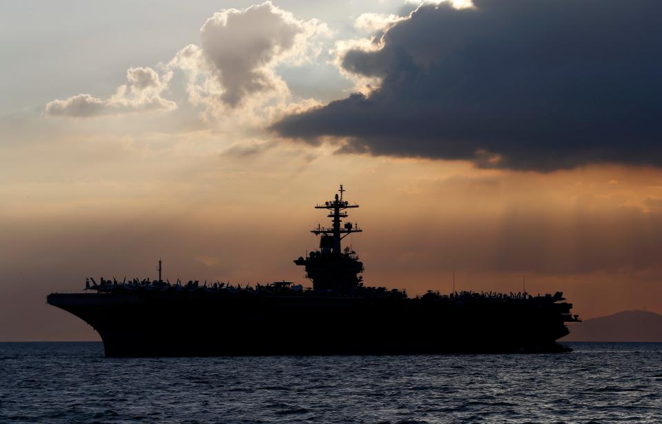 FILE - In this April 13, 2018, file photo the USS Theodore Roosevelt aircraft carrier is anchored off Manila Bay west of Manila, Philippines. The captain of the U.S. Navy aircraft carrier facing a growing outbreak of the coronavirus is asking for permission to isolate the bulk of his roughly 5,000 crew members on shore, which would take the warship out of duty in an effort to save lives. The ship is docked in Guam (AP Photo/Bullit Marquez, File)