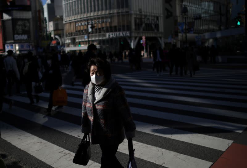 Woman, wearing protective face mask, following an outbreak of the coronavirus, is pictured at the scramble crossing in Shibuya shopping district in Tokyo