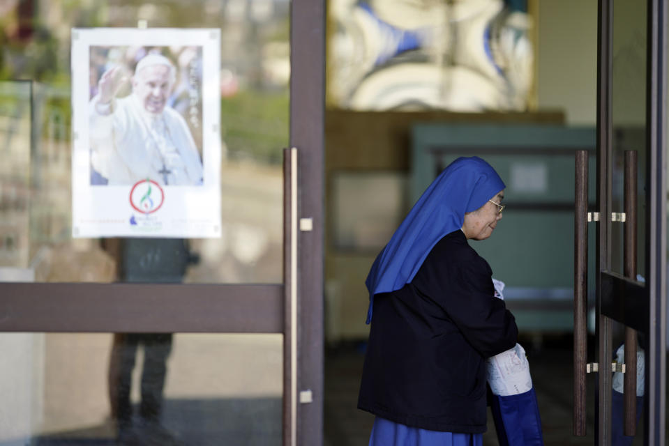 In this Nov. 17, 2019, photo, a Catholic nun walks by a poster of Pope Francis at the Urakami Cathedral in Nagasaki, southern Japan. Pope Francis will start his first official visit to Japan in Nagasaki, ground zero for the Christian experience in a nation where the Catholic leader once dreamed of living as a missionary. (AP Photo/Eugene Hoshiko)