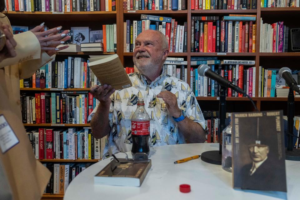 Sarasota author Robert Plunkett, seen signing copies of his reissued 1983 novel “My Search for Warren Harding,” will read from the book July 17 at Bookstore1Sarasota.