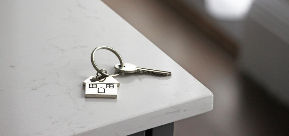 Key with a house-shaped keychain lies on a countertop