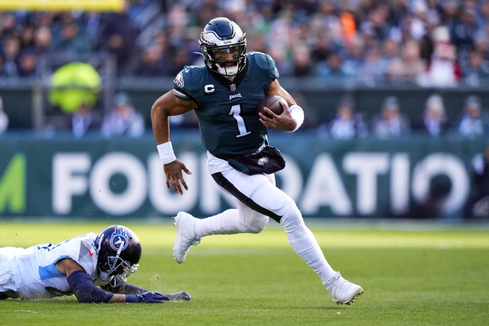 Philadelphia Eagles' Jalen Hurts runs past Tennessee Titans' Andrew Adams during the first half of an NFL football game, Sunday, Dec. 4, 2022, in Philadelphia. (AP Photo/Matt Slocum)