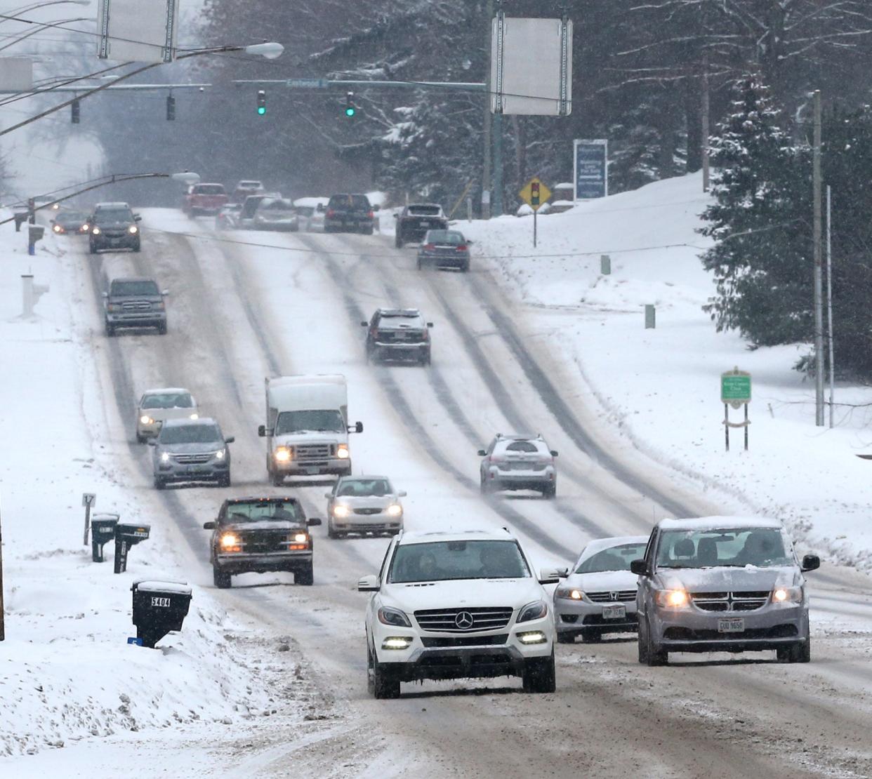 Traffic managed snow covered roadways on Market Avenue N south of 55th Street NW on Monday.