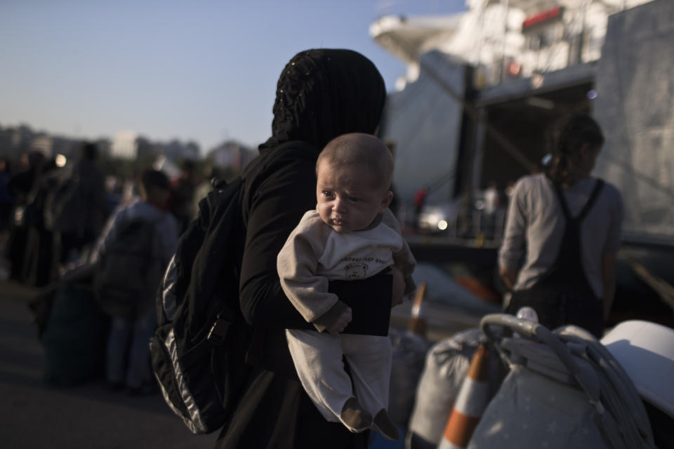 A Syrian woman holds her three month old baby Mohhamed Lousman after they disembark from a ferry, at the port of Piraeus, near Athens, Tuesday, Sept. 25, 2018. About 400 migrants and refugees arrived at the port from the island of Lesbos as authorities have been moving hundreds of migrants deemed to be vulnerable from the overcrowded Moria camp to camps on the mainland.(AP Photo/Petros Giannakouris)