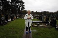 Margaret McKinney holds a running shoe, which her son Brian was wearing when his body was found, as she stands by his grave in Milltown cemetery in West Belfast November 11, 2014. REUTERS/Cathal McNaughton