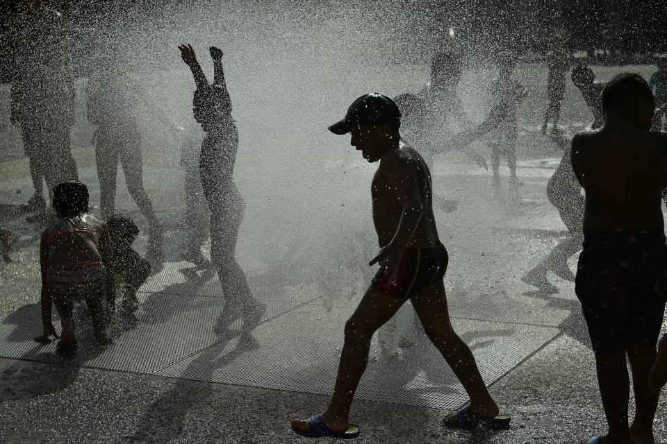 People cool off in a fountain during a hot summer day, in Pamplona, northern Spain, Tuesday, June, 25, 2019. Hot air from Africa is bringing a heat wave to Europe, prompting health warnings about Sahara Desert dust and exceptionally high temperatures in Spain. (AP Photo/Alvaro Barrientos)