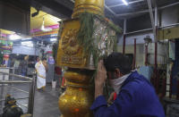 A man wearing a scarf as a precaution against the coronavirus offers prayers at Shakti Ganesh temple in Hyderabad, India, Tuesday, Sept. 22, 2020. (AP Photo/Mahesh Kumar A.)