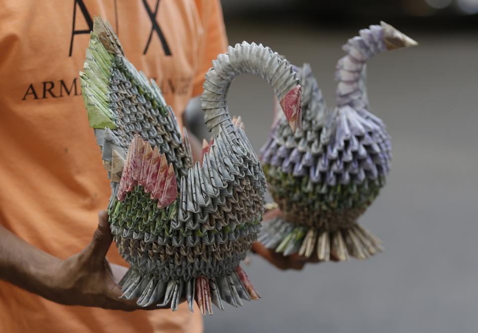 A Venezuelan migrant shows handicrafts made in with devalued Venezuelan currency, in Cucuta, Colombia, Wednesday, Feb. 6, 2019. The Venezuelan military blocked a border bridge where humanitarian aid is expected to arrive with a tanker and two cargo trailers, Colombian officials said Monday, in an apparent bid to stop the loads of food and other supplies from entering the country. (AP Photo/Fernando Vergara)