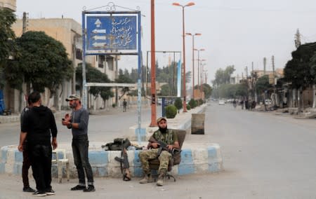 A Turkey-backed Syrian rebel fighter sits on a chair along a street in the border town of Tal Abyad