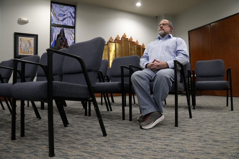 In this Dec. 22, 2022, photo, Shane Woodward poses for a photo in the area of Congregation Beth Israel where he was sitting when taken hostage in Colleyville, Texas. A year ago, a rabbi and three others survived a hostage standoff at their synagogue in Colleyville, Texas. Their trauma did not disappear, though, with the FBI's killing of the pistol-wielding captor. Healing from the Jan. 15, 2022, ordeal is ongoing. (AP Photo/Tony Gutierrez)