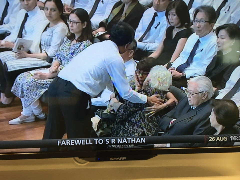 S R Nathan’s son, Osith, comforts his mother, Mrs Nathan, and sister, Juthika, after laying a wreath for his father at the UCC. (Photo: TV screenshot)