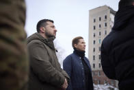 In this photo provided by the Ukrainian Presidential Press Office, Danish Prime Minister Mette Frederiksen, center, and Ukrainian President Volodymyr Zelenskyy look at the site of the recent Russian shelling in Mykolaiv, Ukraine, Monday, Jan. 30, 2023. (Ukrainian Presidential Press Office via AP)