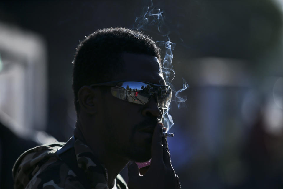 In this Nov. 7, 2018 photo, a Haitian migrant smokes a cigarette as he waits to register for repatriation, in Santiago, Chile. After an unsuccessful migration experience to Chile, 176 Haitians, mostly men, were flown home on a military plane free of charge. (AP Photo/Esteban Felix)