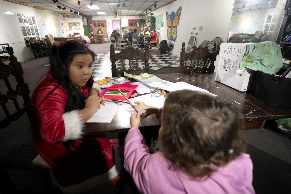 Amy Bautista Lopez, de 7 años, hija de una organizadora comunitaria, enseña las letras en inglés a una niña migrante de 4 años que llegó a Estados Unidos en el último mes, el viernes 15 de diciembre de 2023 en Fort Morgan, Colorado. (AP Foto/Julio Cortez)
