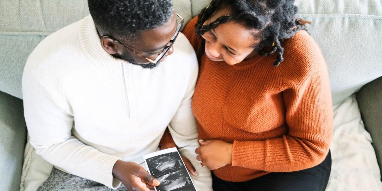 Black couple holding sonogram photos