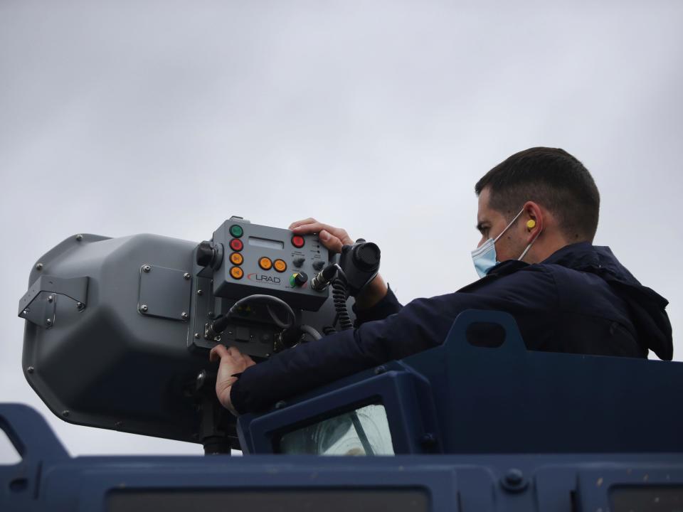 A police officer operates a long-range acoustic device.