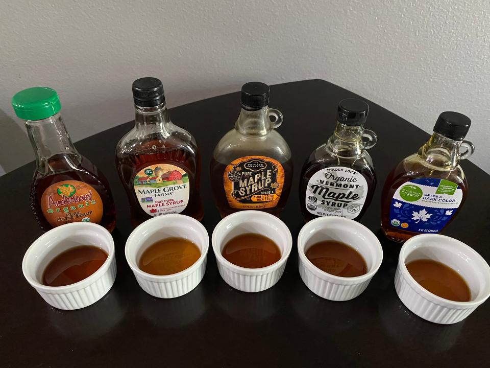 fice brands of maple syrup lined up with small ramekins of the syrup in front of them