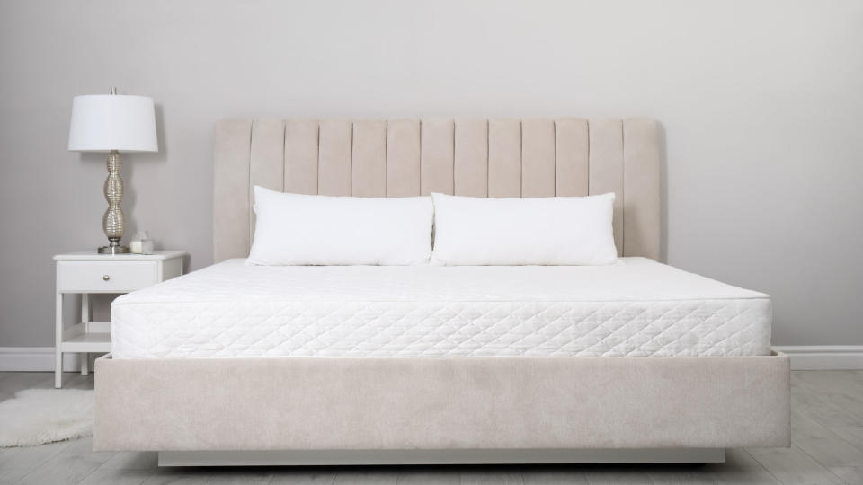  White mattress that comes with a lifetime warranty placed on a beige bedframe. 