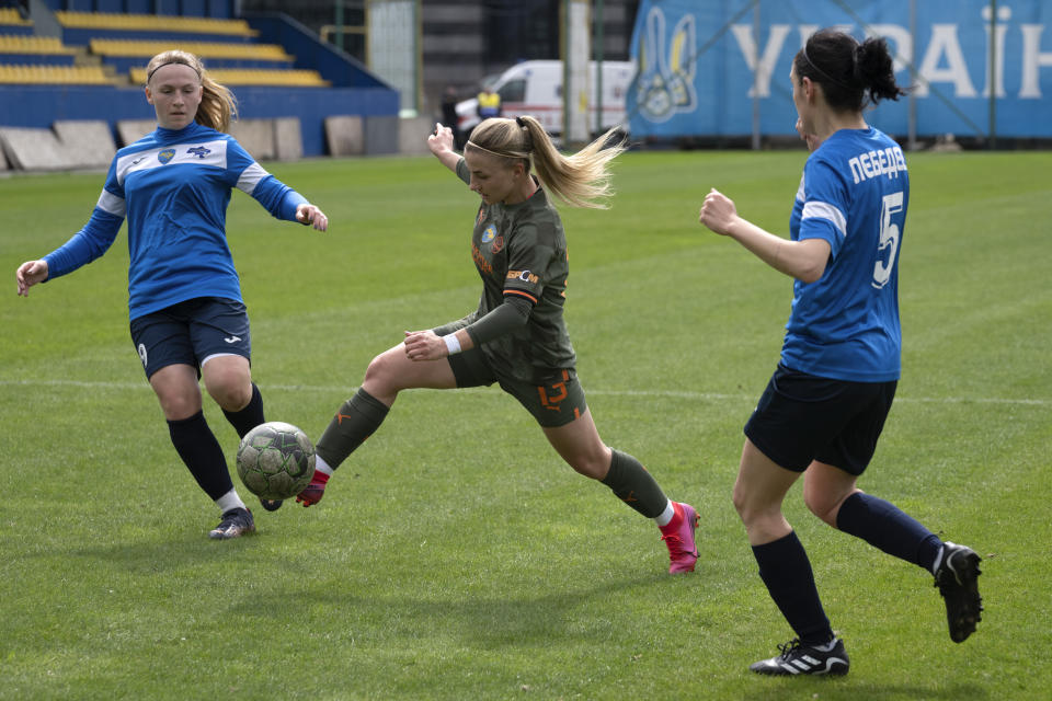 Players of a women's football team from Mariupol and Shakhtar challenge for the ball during Ukrainian championship match in Kyiv, Ukraine, Tuesday, April 18, 2023. After their city was devastated and captured by Russian forces, the team from Mariupol rose from the ashes when they gathered a new team in Kyiv. They continue to play to remind everyone that despite the occupation that will soon hit one year, Mariupol remains a Ukrainian city.(AP Photo/Efrem Lukatsky)