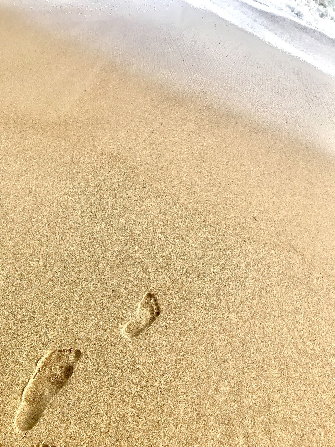 high angle view of footprints on sand at beach in front of surf