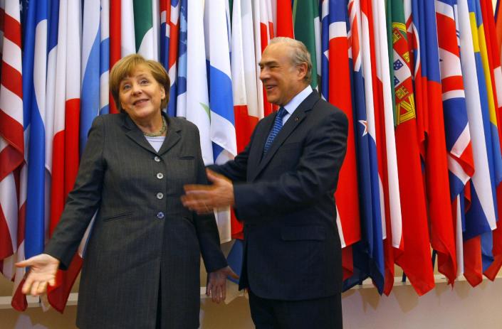 Head of the Organization for Economic Co-operation and Development (OECD) Angel Gurria, centre, and Germany's Chancellor Angela Merkel, react, prior to their meeting at the OECD headquarters in Paris, Wednesday, Feb. 19, 2014. (AP Photo/Michel Spingler)