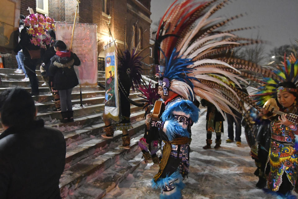 In this Jan. 24, 2020 photo, people in traditional Aztec clothing ascend the steps of the Sagrado Corazon de Jesus church in Minneapolis for a two-day celebration of St. Paul, the patron saint of their Mexican hometown of Axochiapan and nearby villages in the state of Morelos. The celebration is a way to recognize their roots and feel closer to the families and home they left behind. (AP Photo/Jim Mone)