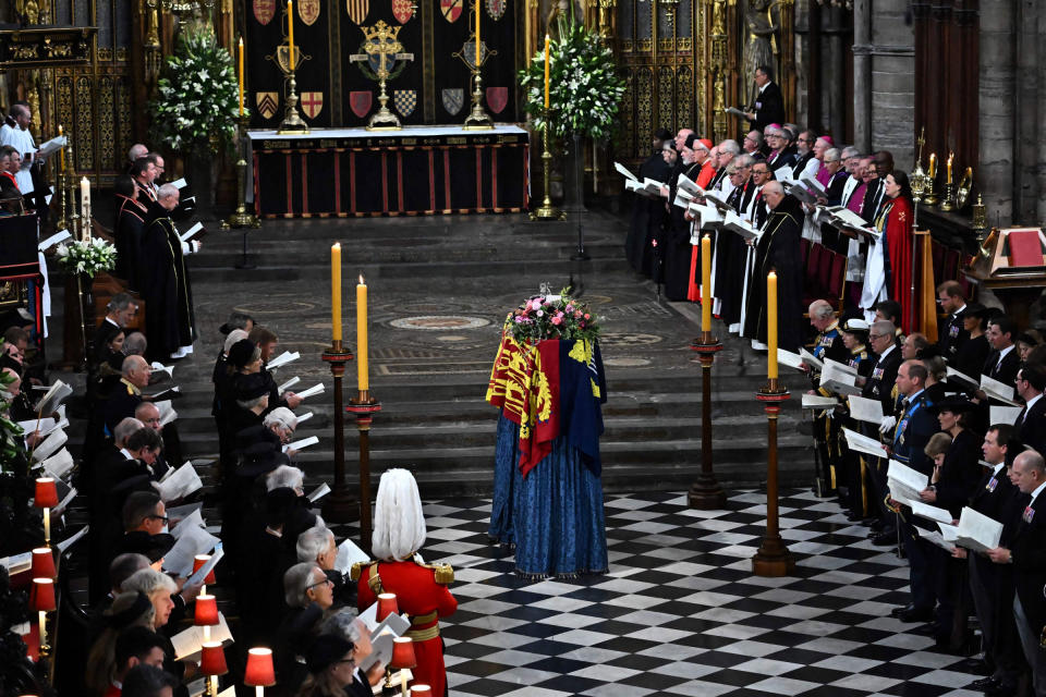 Members of the royal family and guests sing as the coffin of Queen Elizabeth II, draped in the royal standard, lies by the altar during the state funeral service for Queen Elizabeth II at Westminster Abbey in London.<span class="copyright">Ben Stansall—Pool/AFP/Getty Images</span>