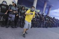 A demonstrator wearing a Brazil jersey films with his cameras in front of riot police during clashes before the World Cup final match between Argentina and Germany in Rio de Janeiro July 13, 2014. REUTERS/Nacho Doce (BRAZIL - Tags: SPORT SOCCER WORLD CUP POLITICS CIVIL UNREST)