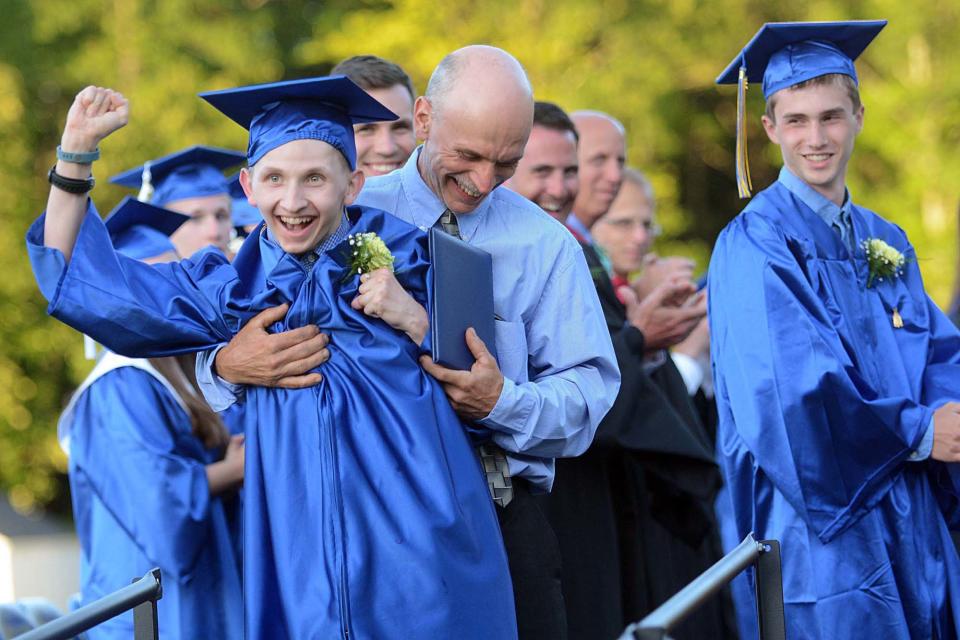 Bacon Academy graduate Jake Shumbo, recovering from a traumatic brain injury, with his father Tom Shumbo, celebrates after getting his diploma June 10, 2016 in Colchester.
