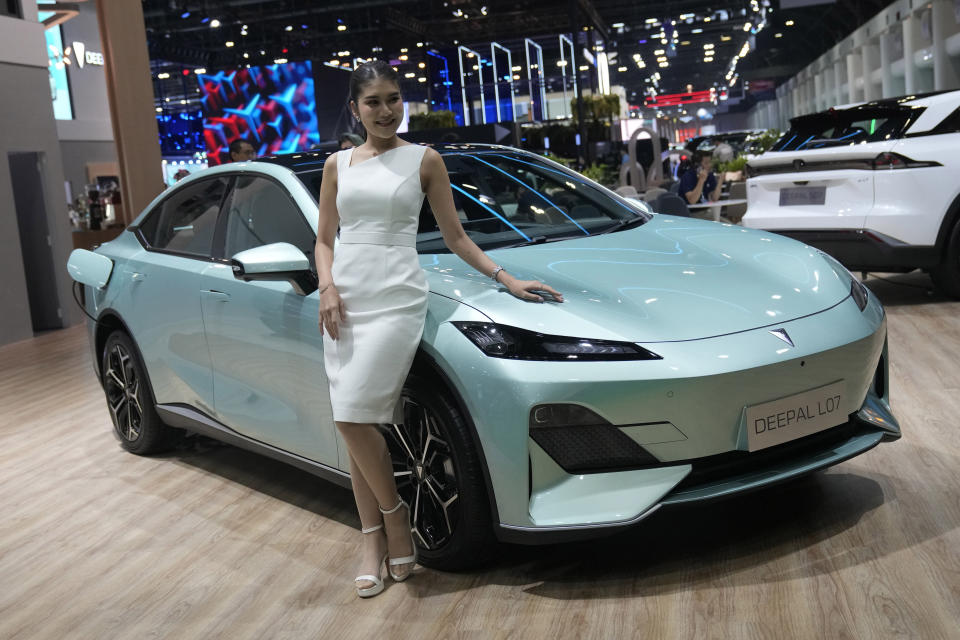 A model stands next to CHANGAN's electric vehicle "Deepal LO7" during the 45th Bangkok Motor Show in Nonthaburi, Thailand, Tuesday, March 26, 2024. (AP Photo/Sakchai Lalit)