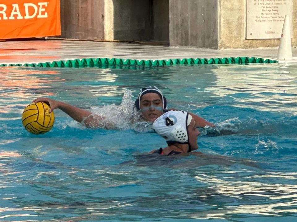 Gulliver’s Reese Rosenthal looks for an opportunity to score while St. Thomas Aquinas’ Rebekah Harkins defends during Friday’s state water polo semifinals at Belen Jesuit.