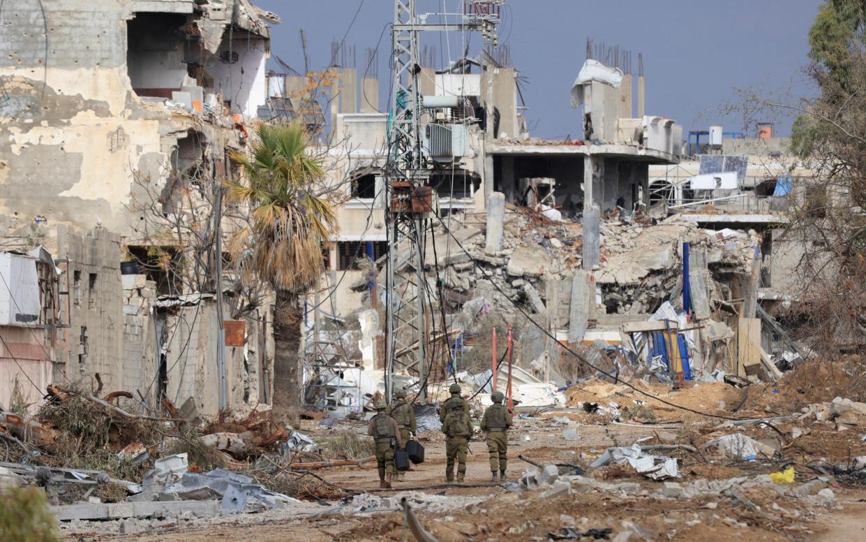 Israeli troops walk past destroyed buildings along the Salaheddine road