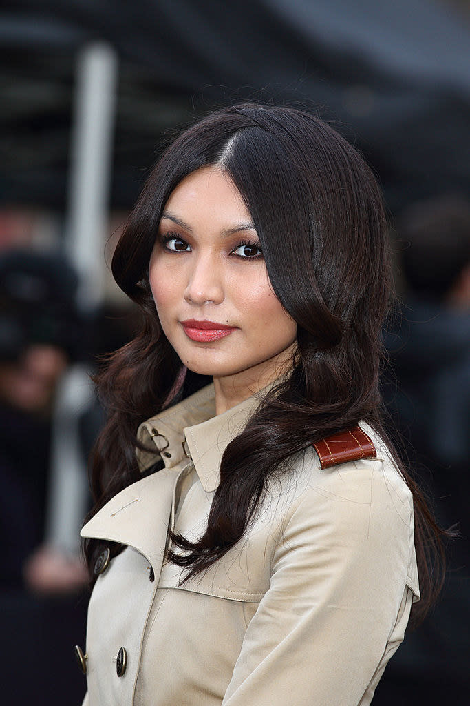 A closeup of Gemma Chan in a trench coat dress