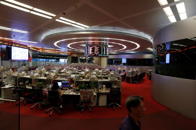 FILE PHOTO: A floor trader walks during afternoon trading at the Hong Kong Stock Exchange in Hong Kong