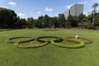 A custodian takes care of plants placed to look like the Olympic rings that local high school students have helped decorate at Hibiya Park in Tokyo Friday, July 16, 2021. (AP Photo/Hiro Komae)