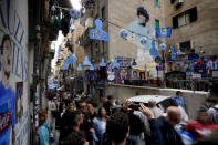 A mural portraying Diego Armando Maradona is seen by banners and writings in support of Napoli soccer team displayed in downtown Naples, Italy, Tuesday, April 18, 2023. It's a celebration more than 30 years in the making, and historically superstitious Napoli fans are already painting the city blue in anticipation of the team's first Italian league title since the days when Diego Maradona played for the club. (AP Photo/Andrew Medichini)