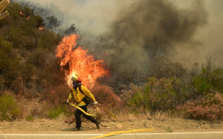 A fireman runs to put out a fire off Placerita Canyon Road in Santa Clarita, California on July 25, 2016